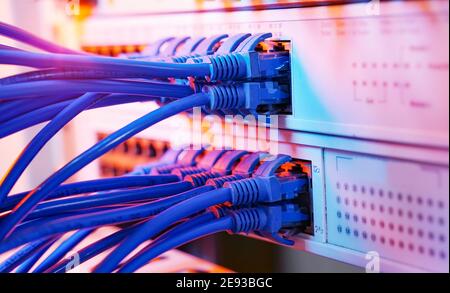 Server rack with blue and red internet patch cord cables connected to black patch panel in data server room Stock Photo