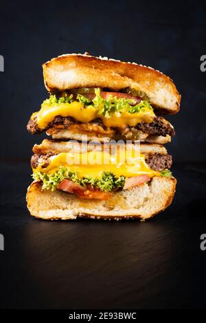 Juicy double decker cheeseburger arranged on a black skipper plate black background, text free space Stock Photo