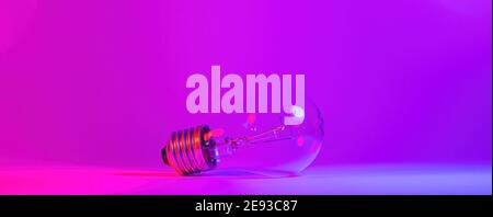 Photo of light bulb lamp in neon light. Ideea concept isolated on pink blue background, for electrician maintenance, craftsman, handyman Stock Photo