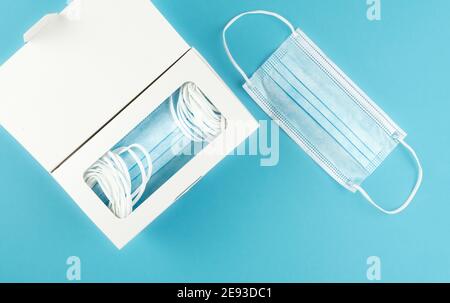 directly above view of medical face masks in dispenser box on blue background Stock Photo