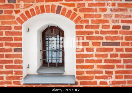 Window with lattice and gray sill. Part of an old building with red clay brick masonry Stock Photo