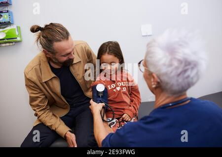 Doctor examining father and daughter in health center Stock Photo