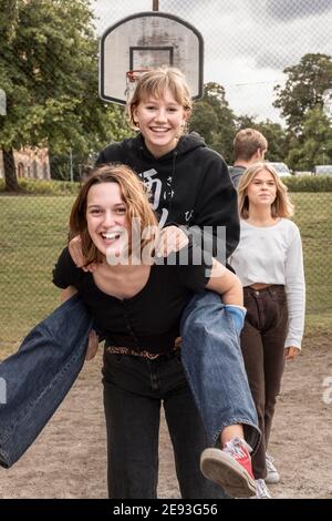 Teenage girl giving friend piggyback ride Stock Photo