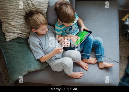 Boys using digital tablet on sofa Stock Photo
