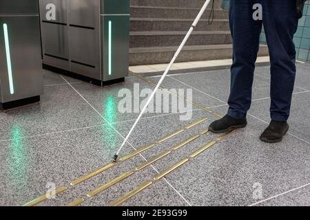 Low section of person with white cane standing at metro station Stock Photo