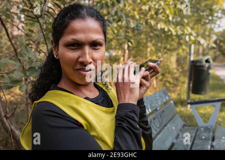 Visually impaired woman sitting on bench and using cell phone Stock Photo