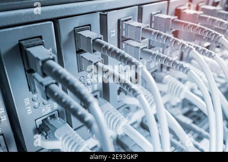 Fiber Optic cables connected to optic ports and Network cables connected to ethernet ports Stock Photo