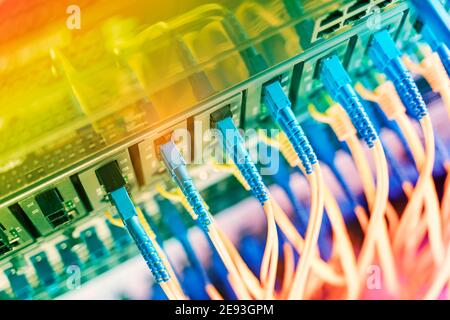 Fiber Optic cables connected to optic ports and Network cables connected to ethernet ports Stock Photo