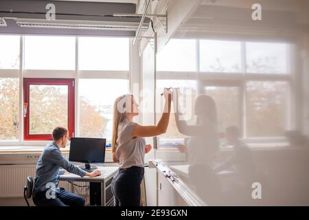 Woman writing on whiteboard in office Stock Photo