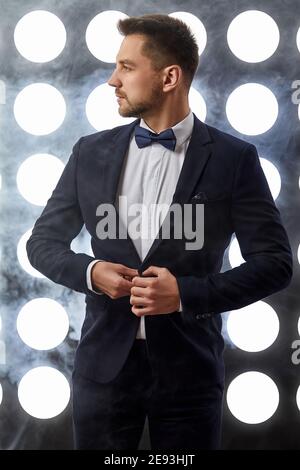 handsome elegant man in tuxedo posing on stage. night life Stock Photo