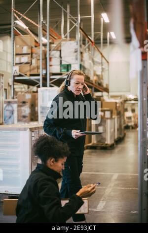 Female manual workers analyzing while holding digital tablet at logistics warehouse Stock Photo