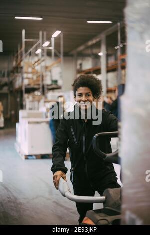 Portrait of smiling female warehouse worker operating machinery Stock Photo
