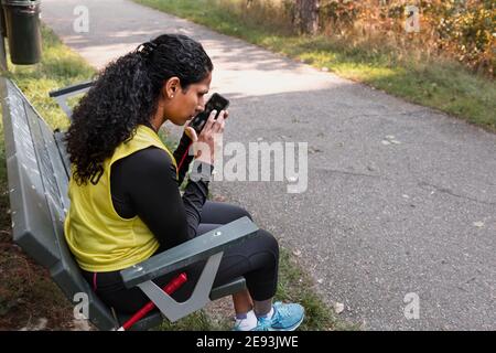 Visually impaired woman sitting on bench and using cell phone Stock Photo