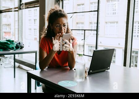 Businesswoman using smart phone while sitting at desk in office Stock Photo