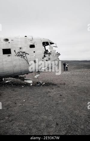 Tourists taking pictures at the remote and eerie Dakota plane wreckage in the black sand plain desert of Sólheimasandur in south Iceland. Stock Photo