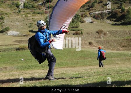 ALPES, FRANCE - Jun 26, 2018: Paraglider inflating his wing before taking off in a small valley surrounded by mountains in the French Alps Stock Photo