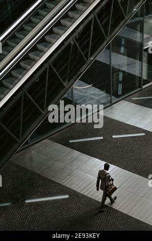 Rear view of businessman walking by escalator on walkway Stock Photo