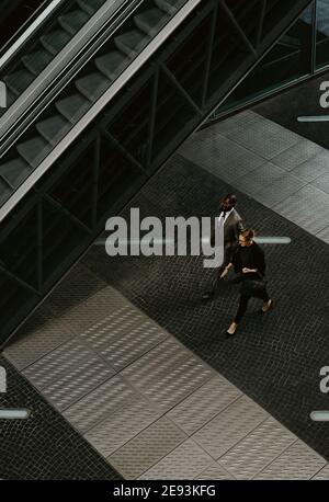 High angle view of male and female entrepreneurs walking by escalator on walkway Stock Photo