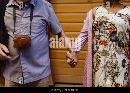 Midsection of senior couple holding hands against wall Stock Photo