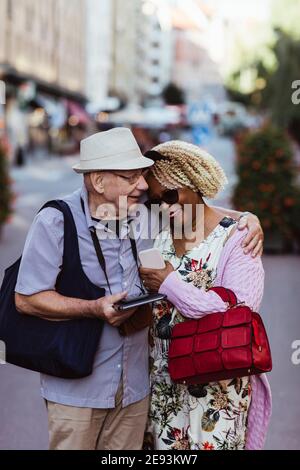 Senior man embracing woman while standing on street in city Stock Photo
