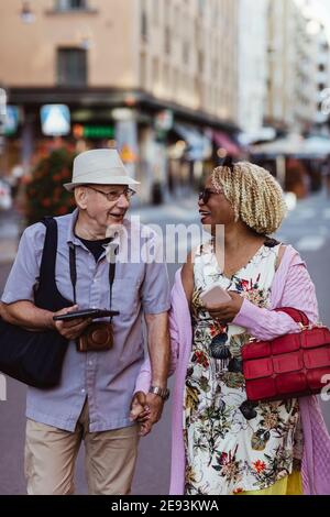 Happy senior couple holding hands walking in city Stock Photo