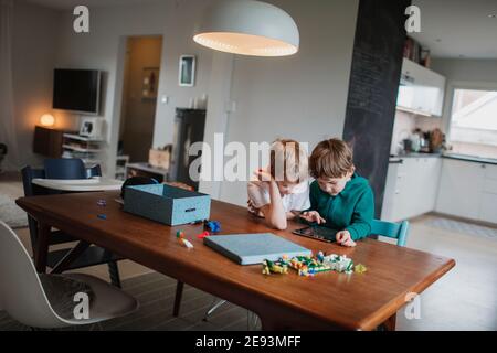 Boys sitting together at table and using digital tablet Stock Photo