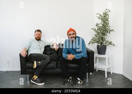 Smiling male coworkers sitting on sofa Stock Photo