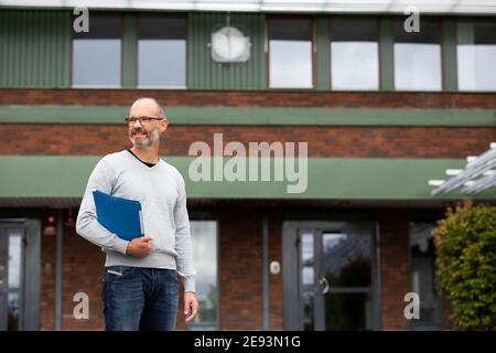 Teacher standing in front of school Stock Photo