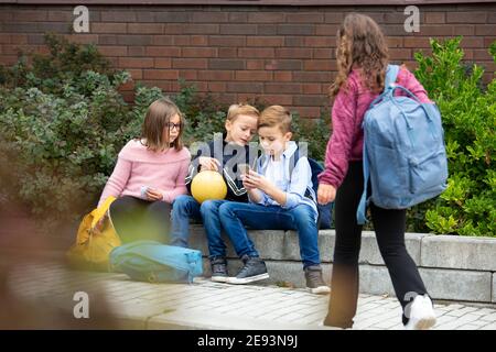 Children looking at cell phone in front of school building Stock Photo