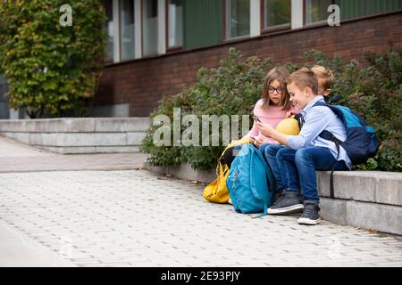 Children looking at cell phone in front of school building Stock Photo