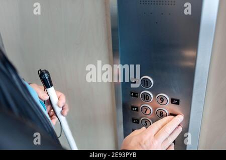 Person with white cane using elevator Stock Photo