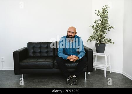Smiling man sitting on sofa Stock Photo