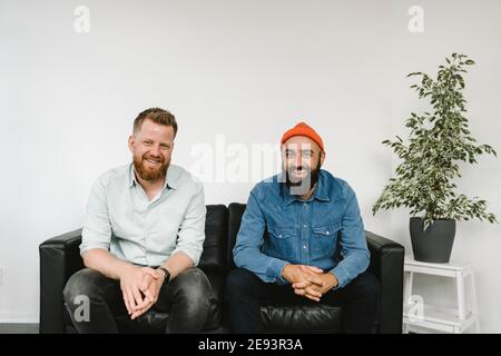 Smiling male coworkers siting on sofa Stock Photo