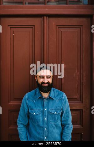 Smiling man standing against door Stock Photo