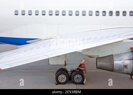 Engine on white fuselage with portholes of passenger plane, jet turbine, windows, wing, aircraft detail, aviation and aerospace industry Stock Photo