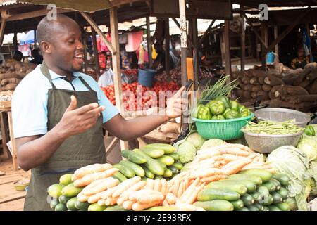 an african market seller holding his phone while smiling Stock Photo