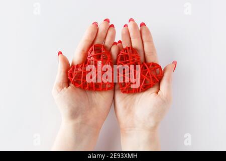 Two red hearts in open palms on  white background, symbol of the day of lovers Stock Photo