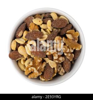 Assorted nuts in a white bowl on a red background top view. Stock Photo