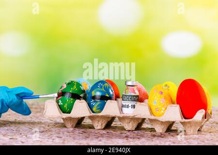 Hands in medical gloves paints black line continue to chicken Easter eggs from to the coronavirus vaccine. Easter 2021 holiday concept due to covid 19 Stock Photo