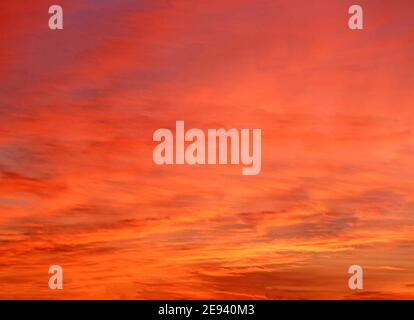 Abstract 1980s background film image of vivid dramatic summer sunset sky glow reflecting on a cloud base varying between discernible horizontal banding layers with fiery orange red yellow colours to overall soft smooth tints above Essex England UK 80s archival historical archive image Stock Photo