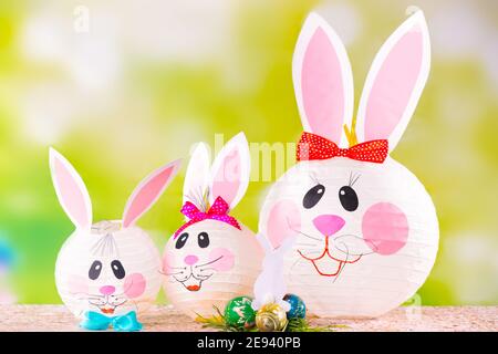 Family of decorative handmade Easter bunnies on a green background. Preparation for the holiday with paper crafts decoration. Mummy rabbit and her Stock Photo