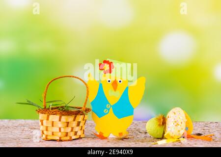 Decorative small Easter basket with fresh grass and cardboard illuminating handcraft chick on a green background. Happy Easter inspiration art with Stock Photo