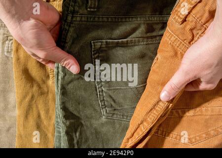 Hands select corduroy trousers lying on the counter. Shopping.  Stock Photo