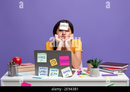 Tired indian woman sitting at desk with sticky notes Stock Photo