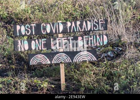 Riverside sign sayin 'Post Covid Paradise - No One Left Behind' Stock Photo