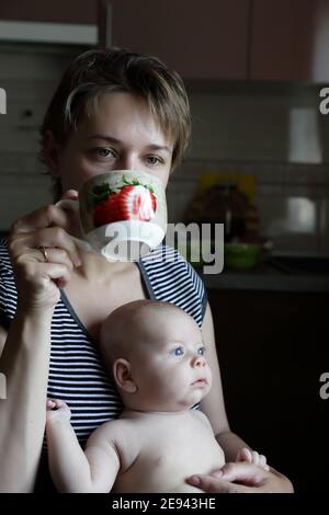 Mother holding her son a drinking tea at home Stock Photo