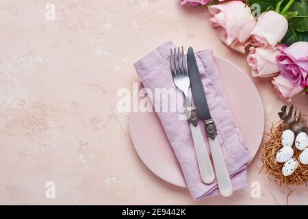Easter spring greeting table setting with decorated with roses and nest with Easter eggs on blue color background. Top view. Space for text. Stock Photo