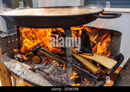 Valencian Paella being cooked on a barbecue with lots of fine oak wood. Spanish typical food. Selective focus. Healthy food concept Stock Photo