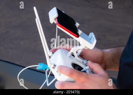Close up of drone pilot hands controlling aircraft with remote control transmitter outdoors Stock Photo