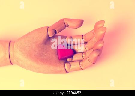 Classic wooden dummy hand holds red heart Stock Photo